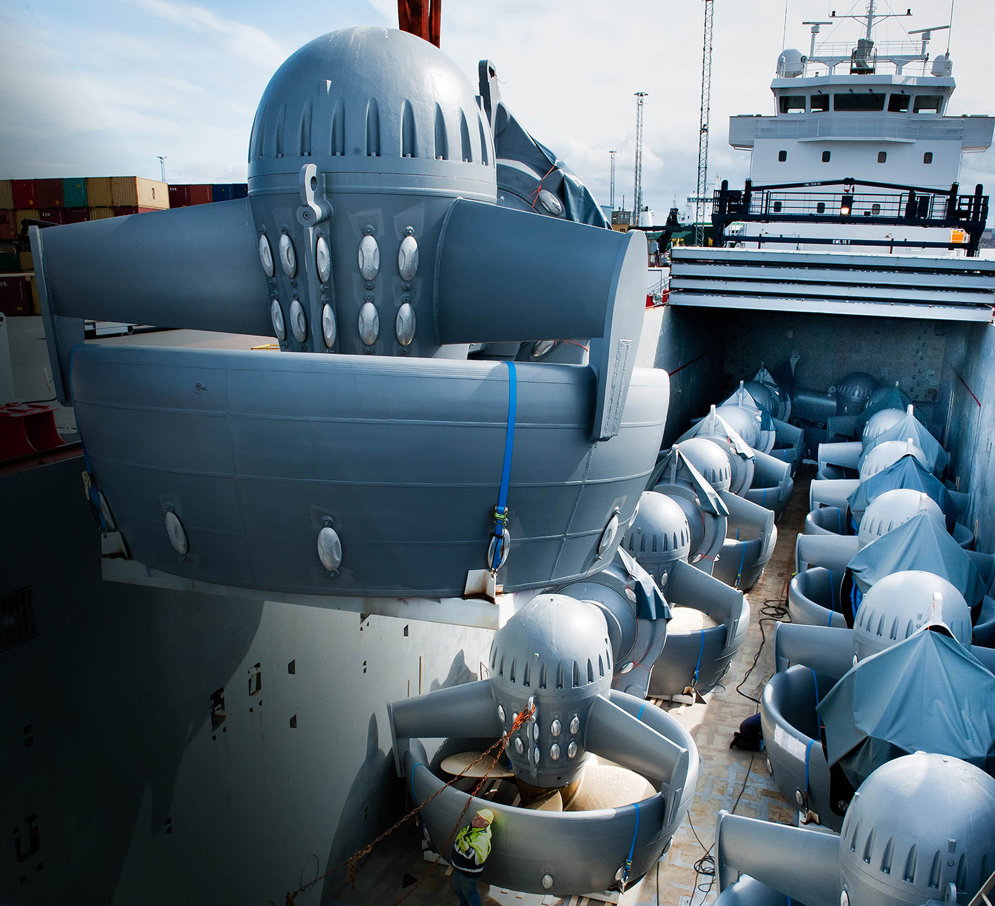2 rows of thrusters on the deck of a transport ship. One more thruster is being loaded onboard.