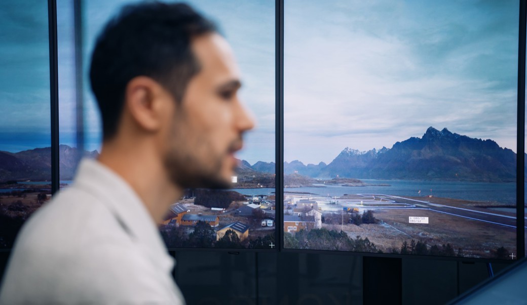 Image of man working on comouter with screens in the background