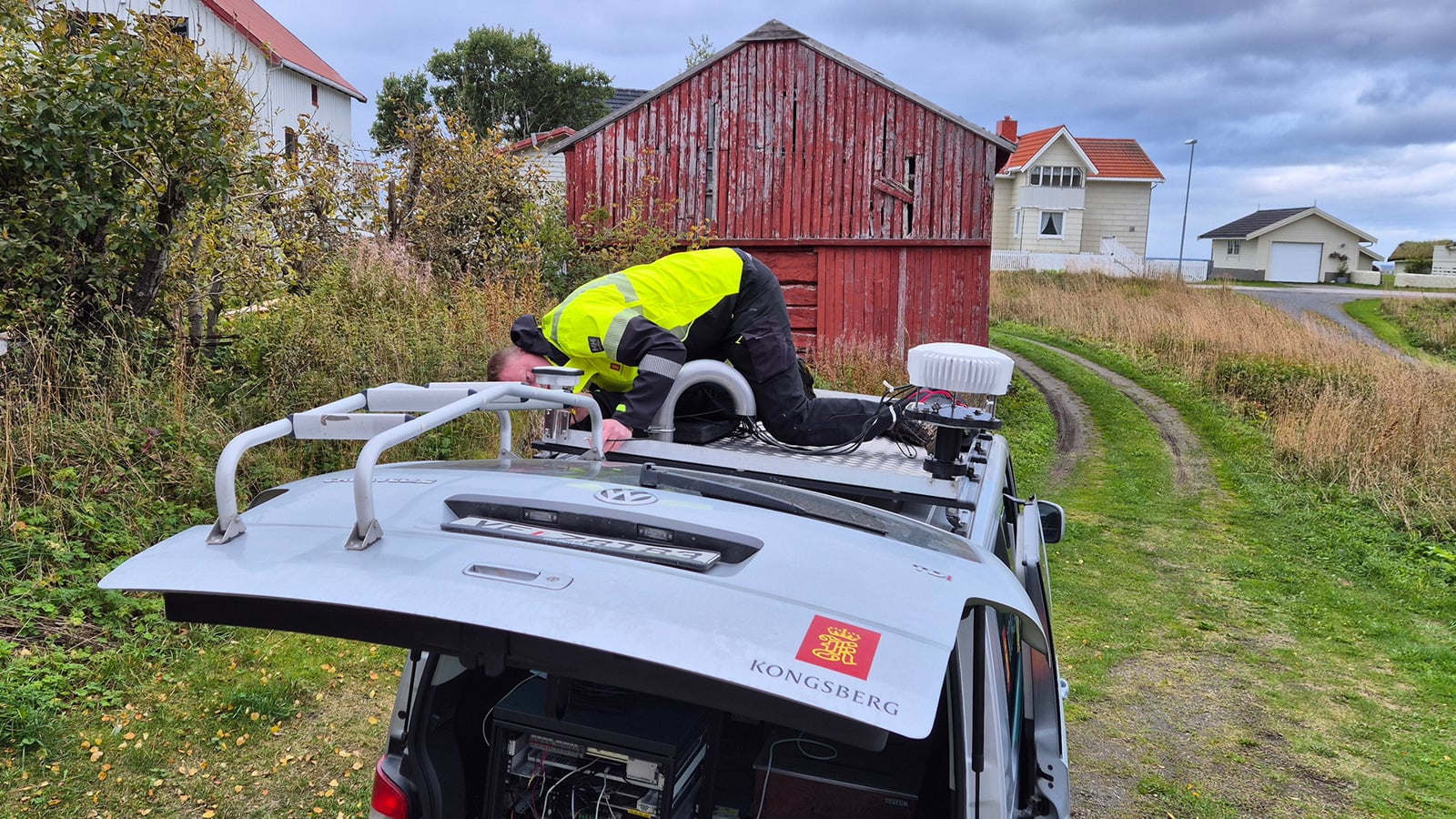 Man on top of car, mounting test equipment.