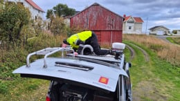 Man on top of car, mounting test equipment.