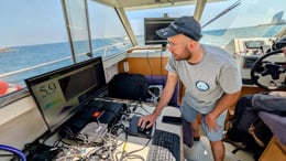 A man working on a computer on board a boat.