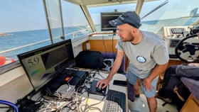 A man working on a computer on board a boat.