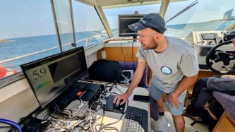 A man working on a computer on board a boat.