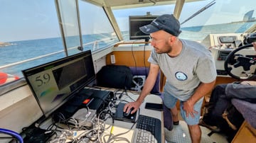 A man working on a computer on board a boat.